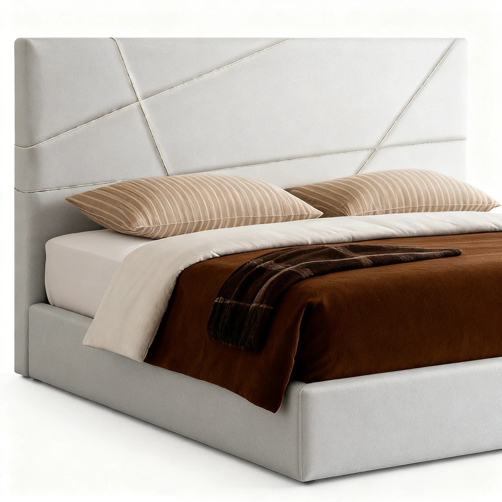Cama estofada moderna com cabeceira branca, edredão castanho e almofadas listradas.